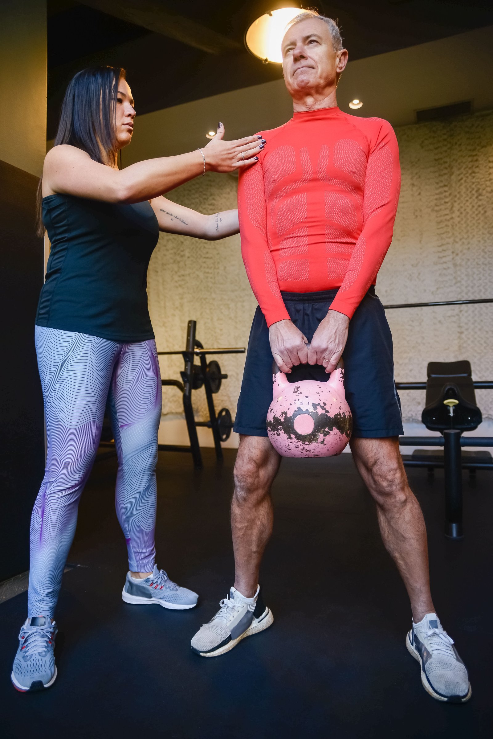 entrenador y adulto mayor leventando pesa